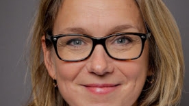Portrett av en kvinne med briller som smiler.