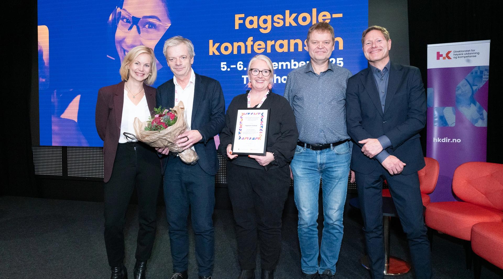 Sveinung Skule og Sigrun Aasland sammen med glade representanter, som holder diplom og blomster, fra Fagskulen Vestland på scenen under Fagskolekonferansen 2025.