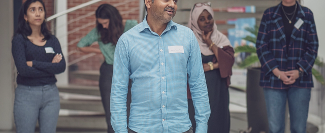 En mann i forgrunnen av bildet, og fire kvinner står med rundt i bakgrunnen.