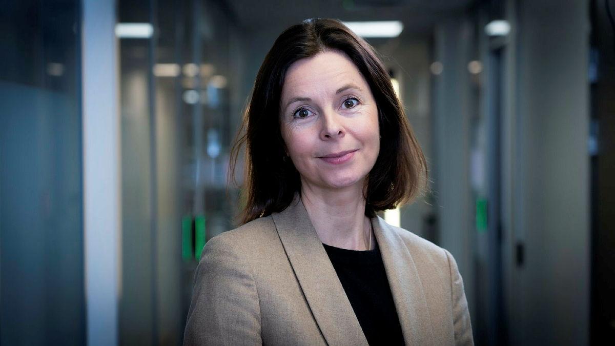 Kristine Offerdal står i en kontorgang og ser mot kamera.