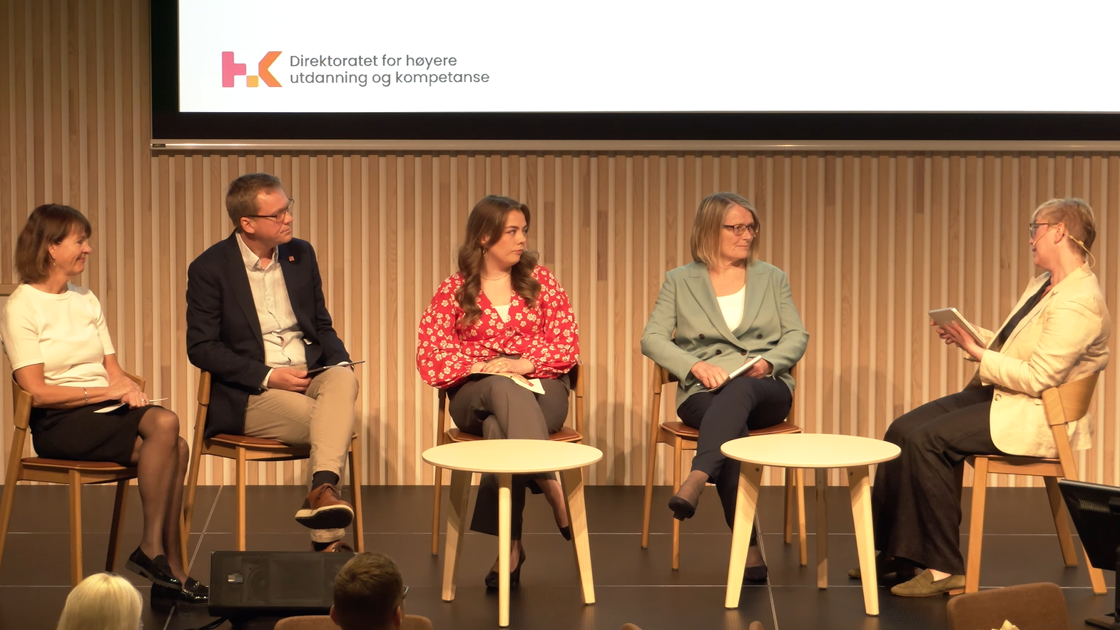 Fire kvinner og en mann på scenen i en panelsamtale