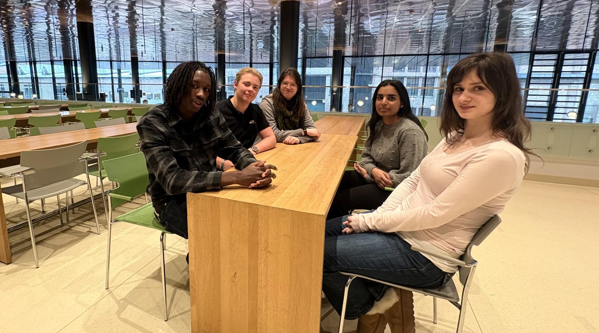 Fem elever sitter rundt et bord