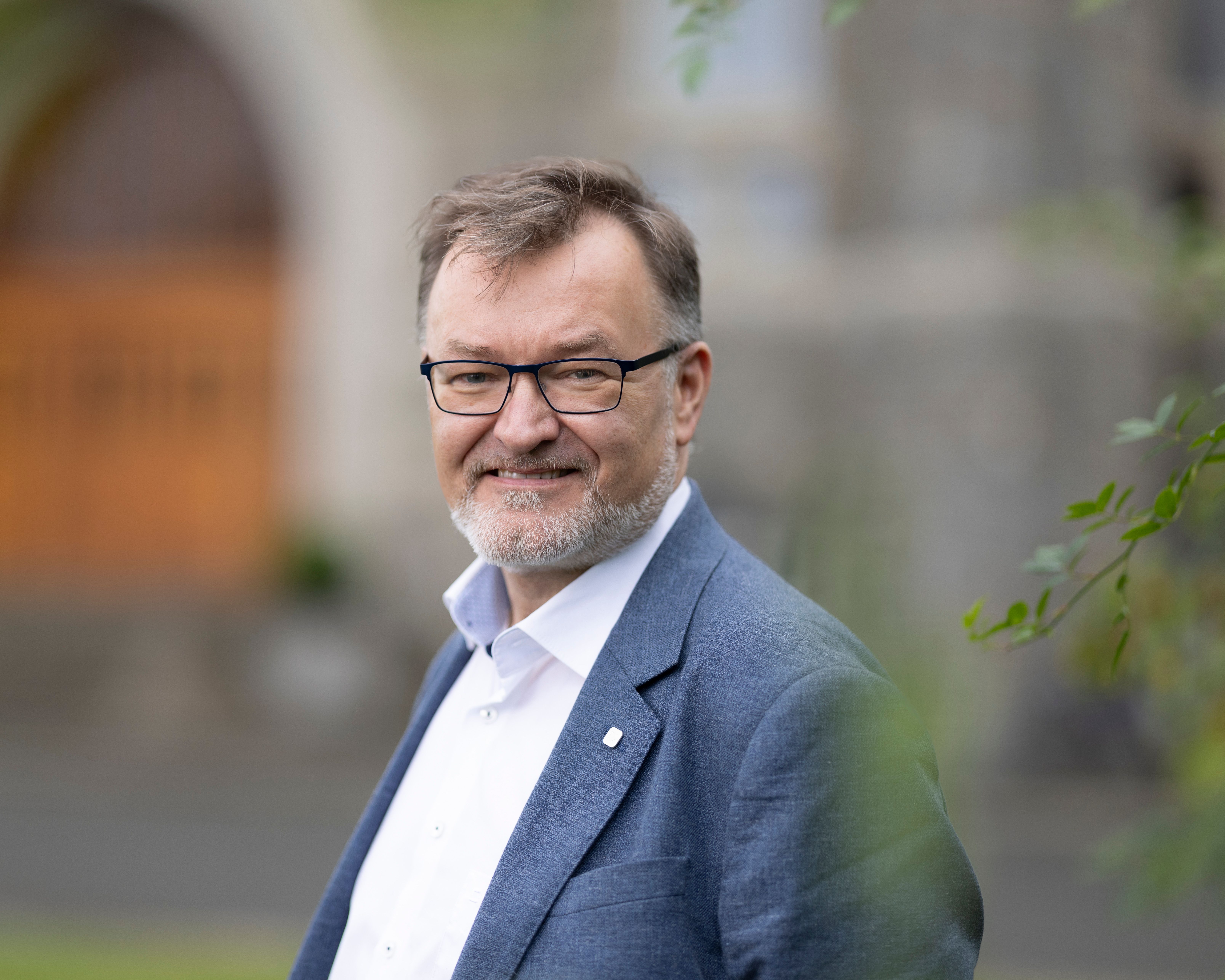 Geir Egil Dahle Øien smiler mot kamera. Han har på seg briller, hvit skjorte og blå dressjakke.