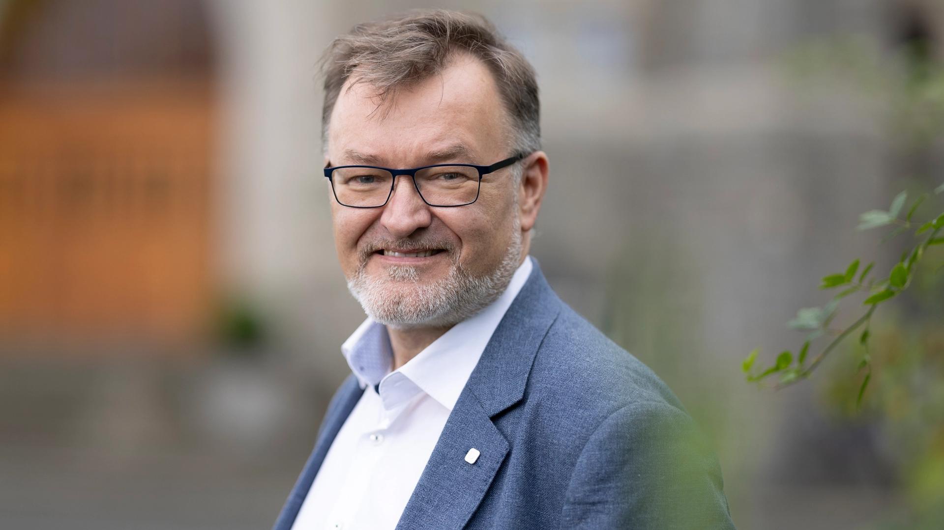 Geir Egil Dahle Øien smiler mot kamera. Han har på seg briller, hvit skjorte og blå dressjakke.