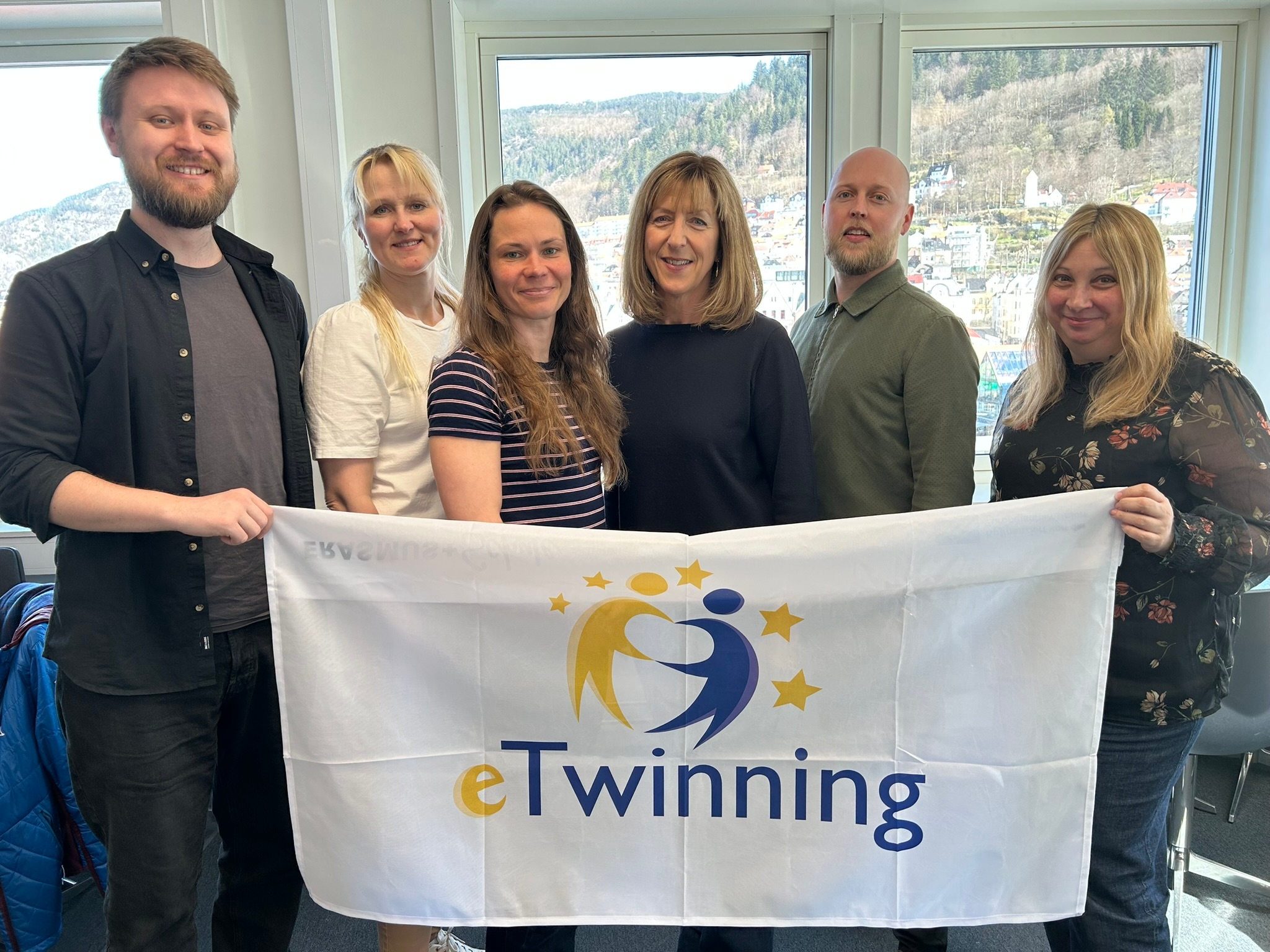 To menn og fire kvinner smiler entusiastisk til kameraet.