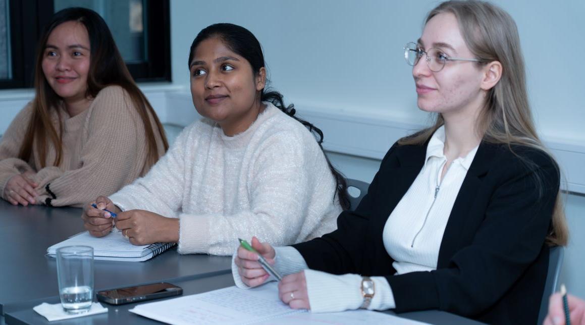 Tre voksne elever sitter i et klasserom