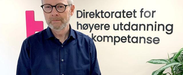 Mann i halvprofil ser i kamera og smiler.