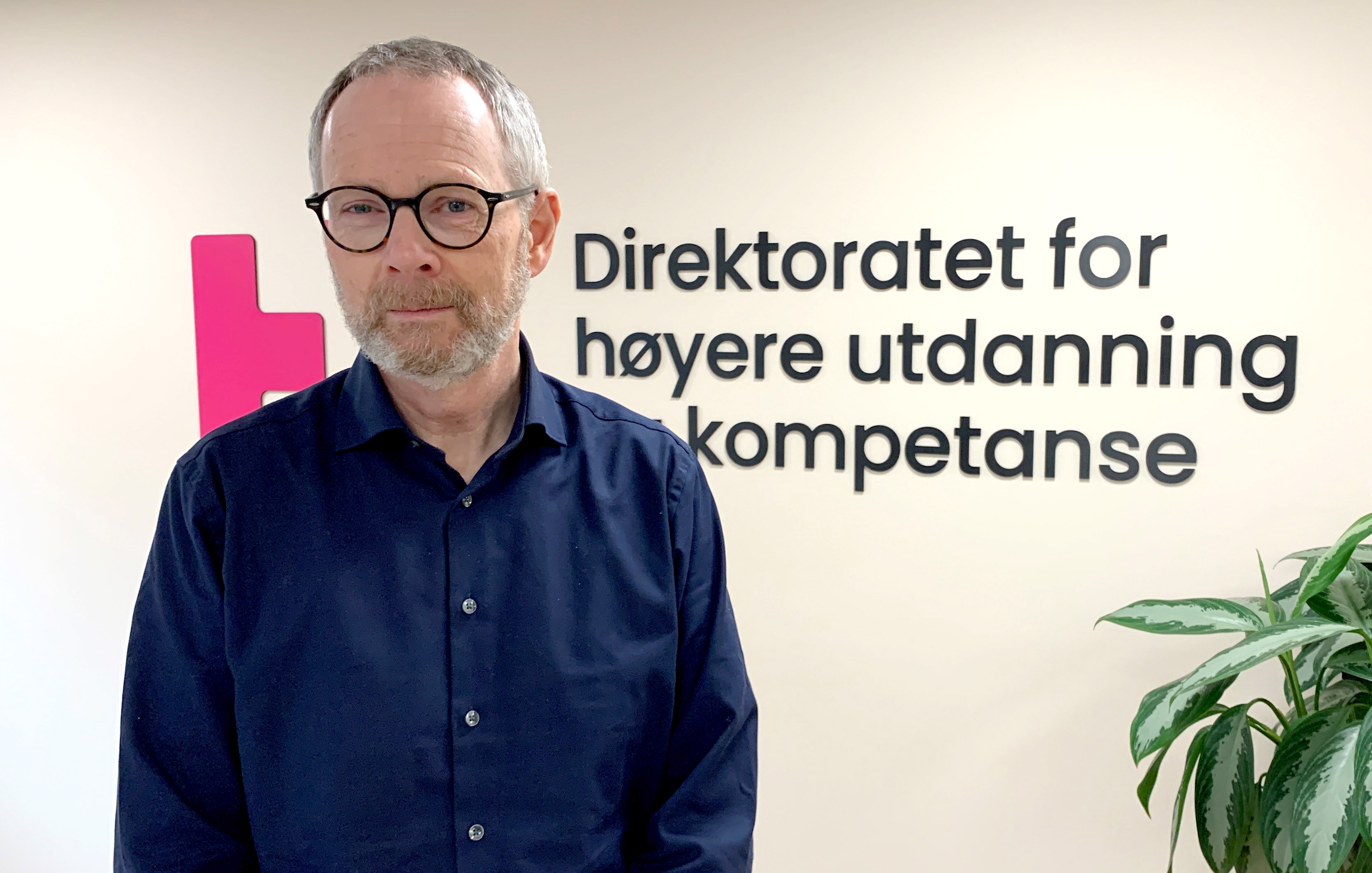 Mann i halvprofil ser i kamera og smiler.