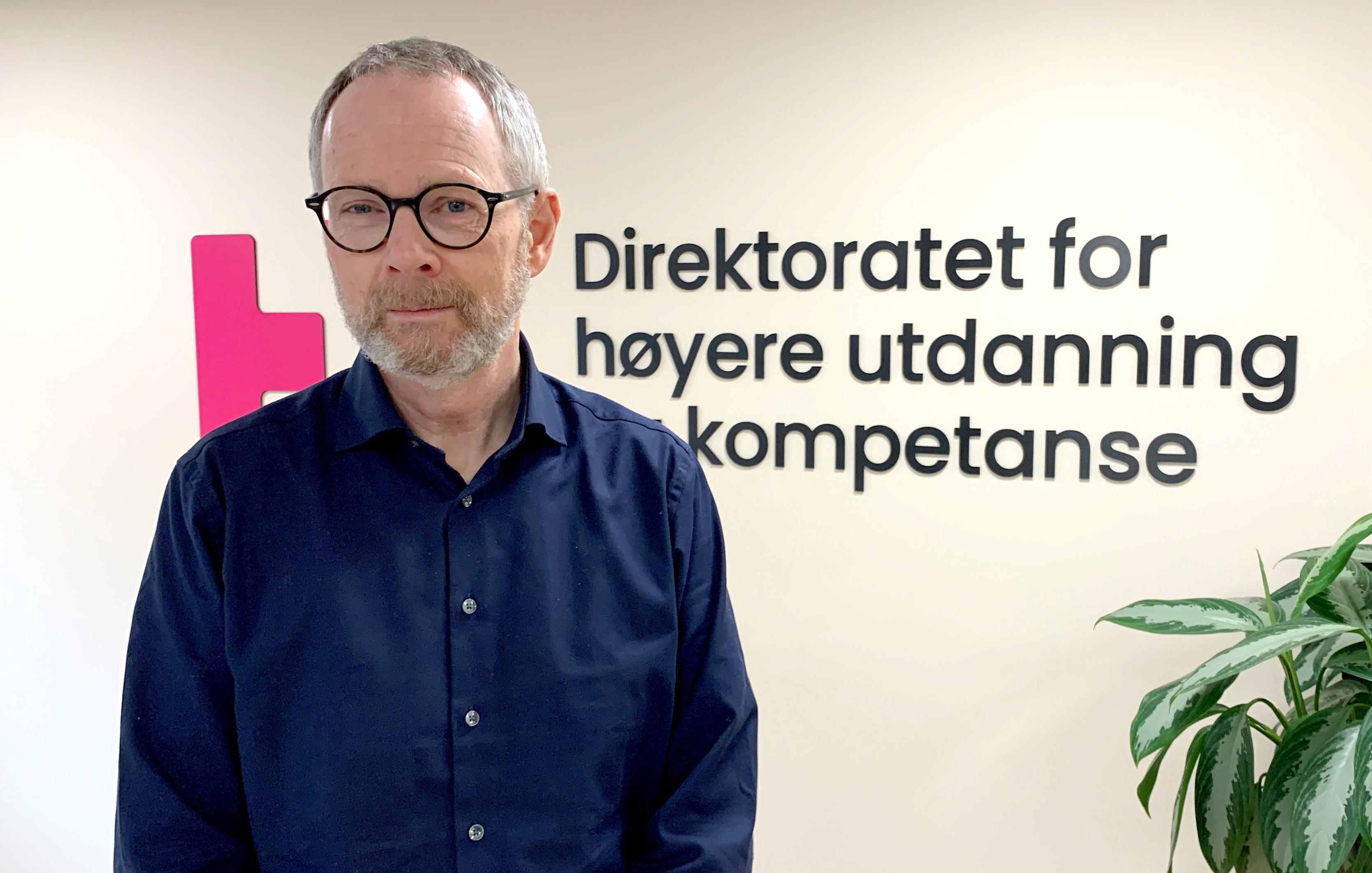 Mann i halvprofil ser i kamera og smiler.