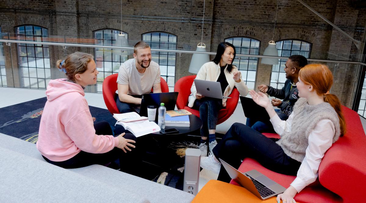 Fem studenter sittende i samtale