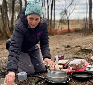 Kvinne i naturen som forbereder mat på stormkjøkken