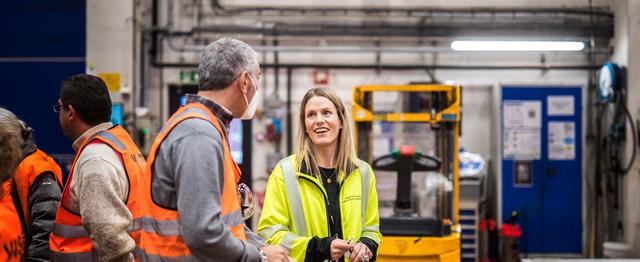 Mann i oransje refleksvest snakker med kvinne med gul arbeidsjakke.