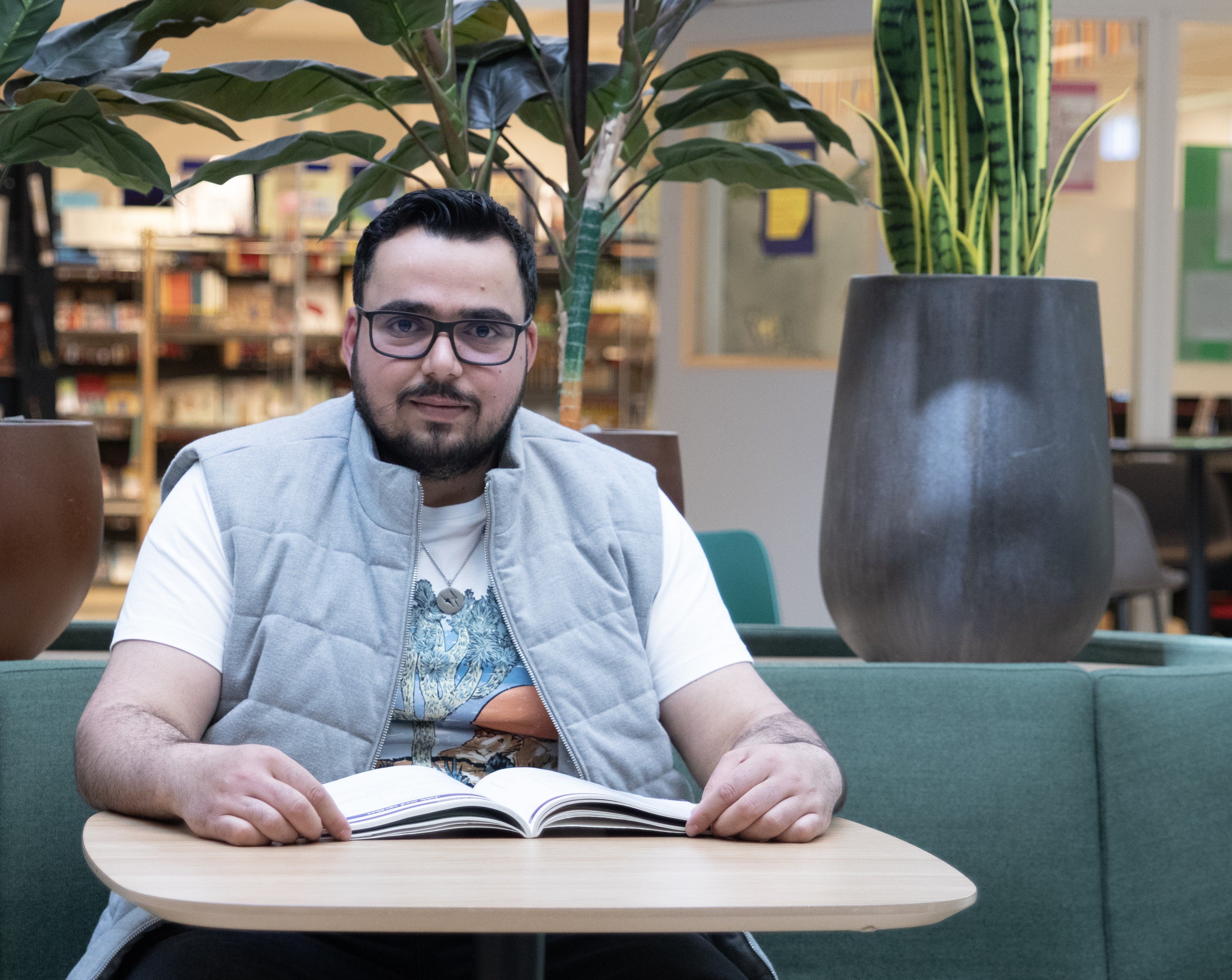 Ahmad Alshahad deltok på livsmestringskurset ved Oslo VO Helsfyr. På bildet sitter han ved et bord med en åpen bok i et læringsmiljø.