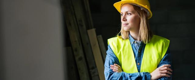 Kvinnelig håndverker med hjelm på byggeplass
