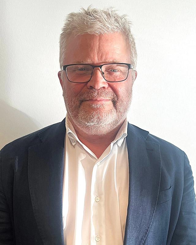 Portrettbilde av mann i dress med briller.