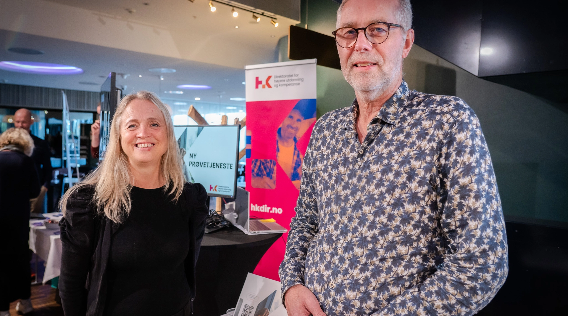 En mann og en kvinne på konferansestand smiler