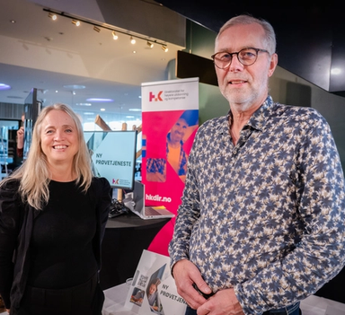 En mann og en kvinne på konferansestand smiler