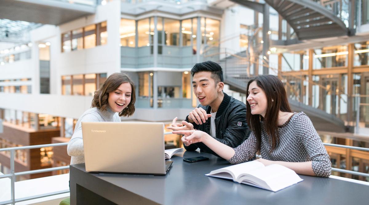 Tre studenter, en mann og to kvinner ser på en laptop