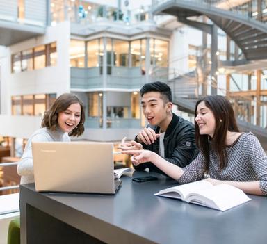 Tre studenter, en mann og to kvinner ser på en laptop