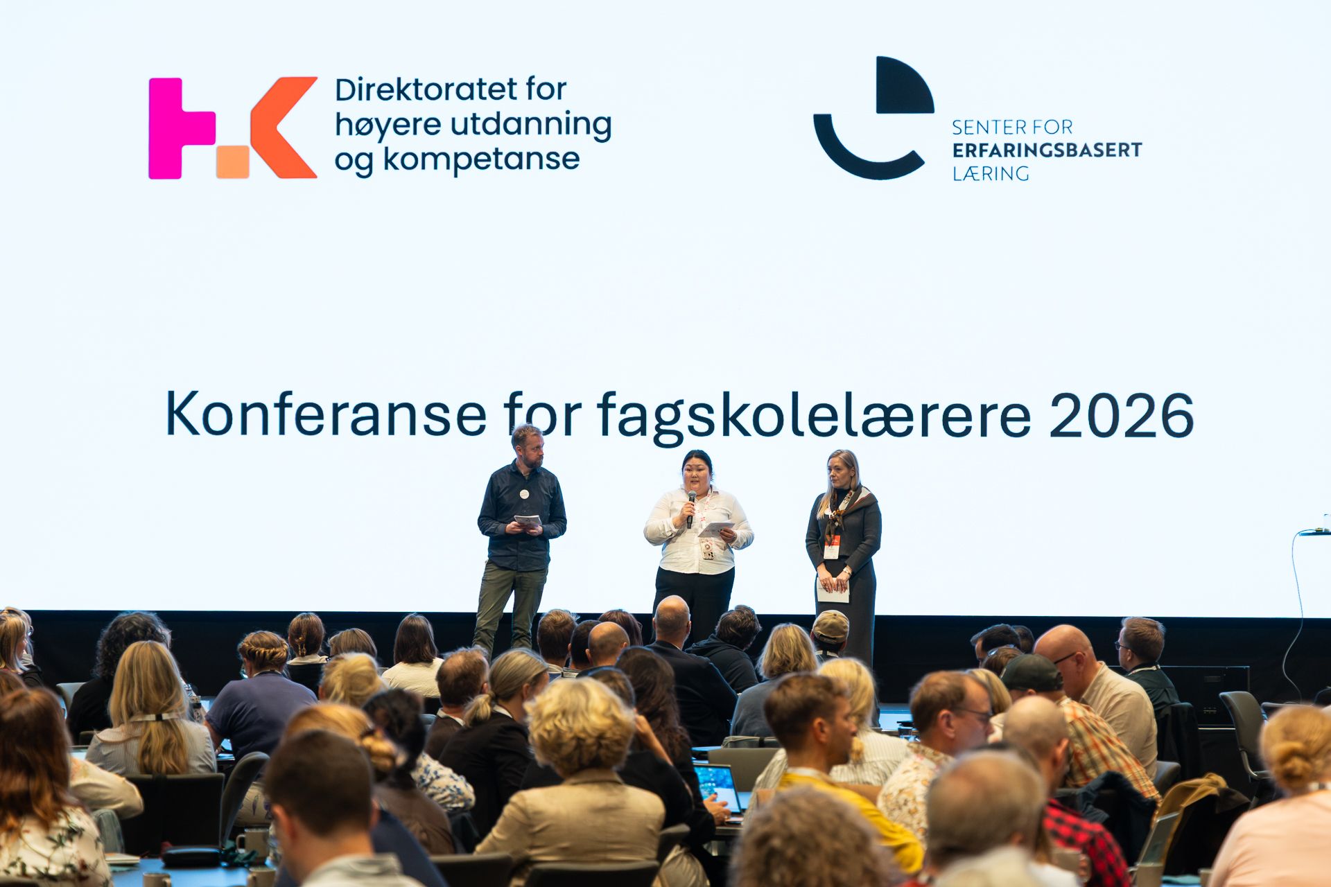 Sal med mange konferansedeltakere, tre mennesker på scenen. På skjermen står det Konferanse for fagskolelærere 2026.