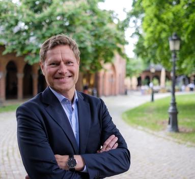 Mann i dress står utenfor og ser mot kamera