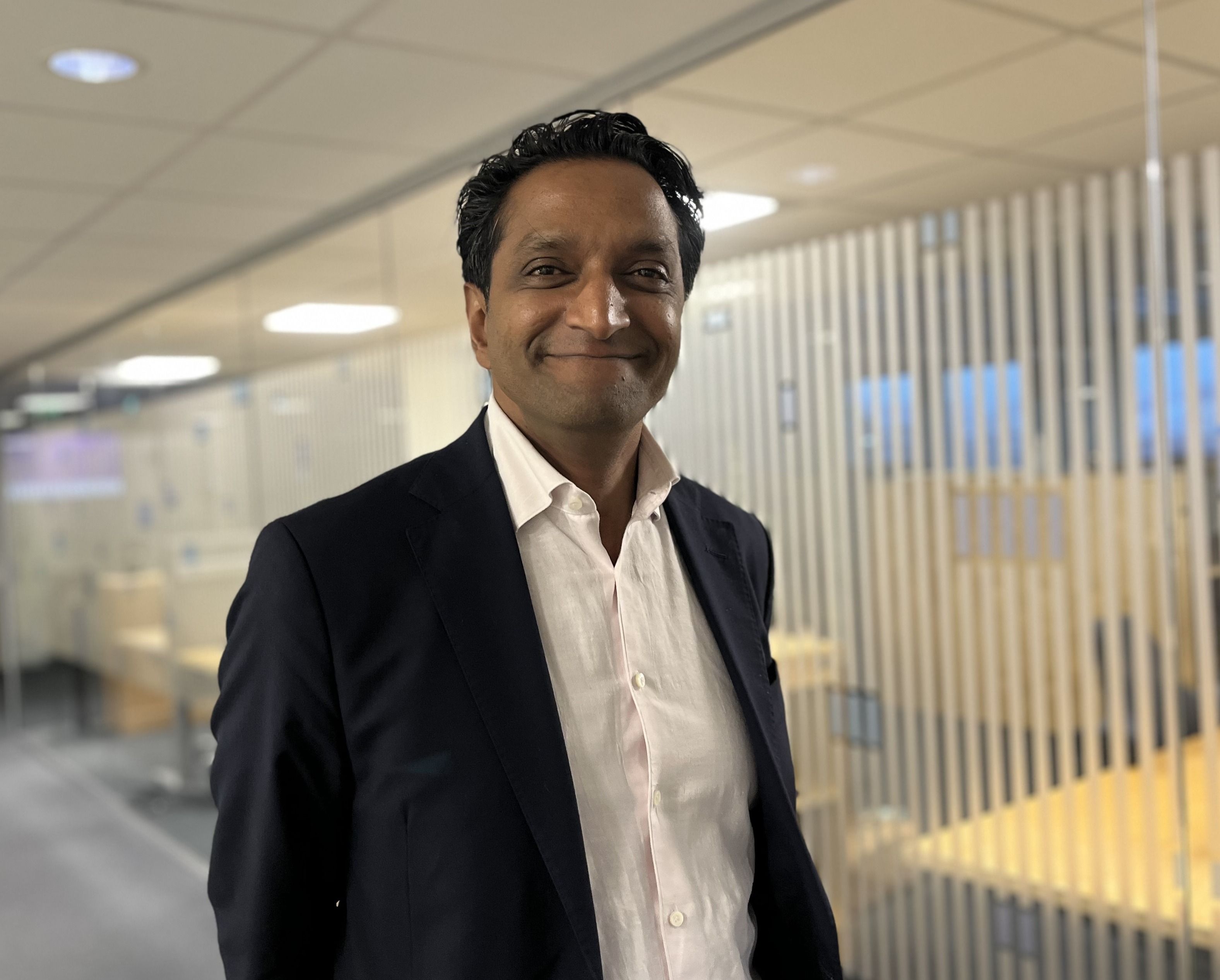 Mann i dress, ser mot kamera og smiler