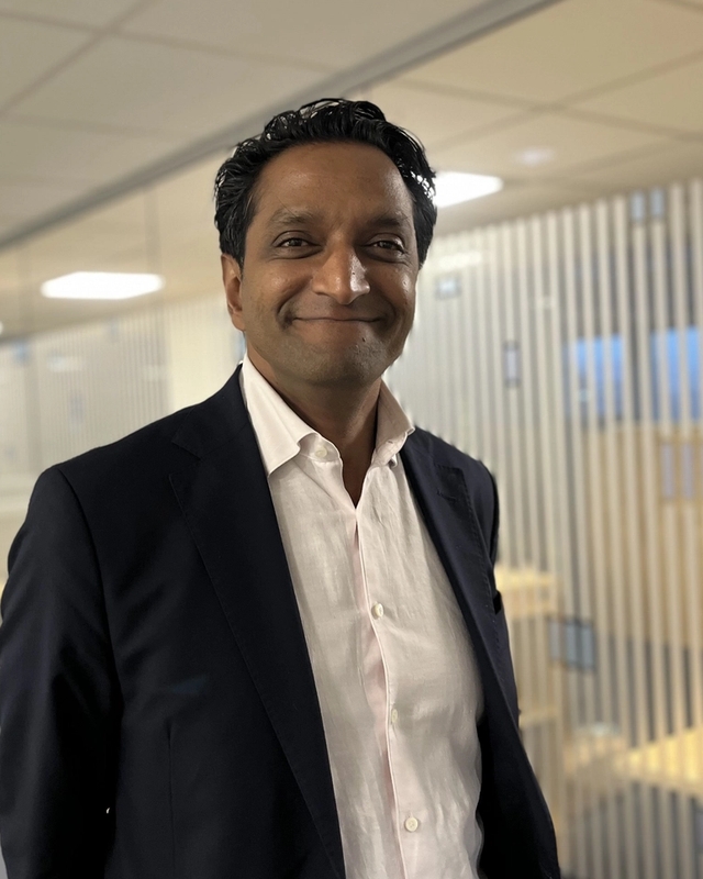 Mann i dress, ser mot kamera og smiler