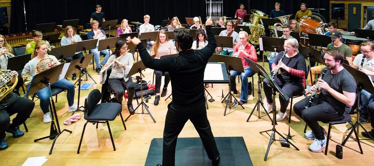 En dirigent står foran et orkester og dirigerer.