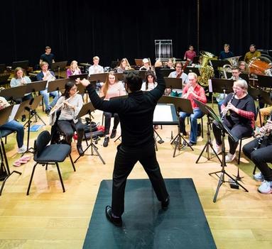 En dirigent står foran et orkester og dirigerer. 