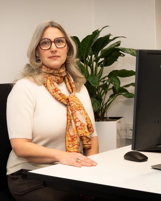 Kvinne som arbeider på PC, ser mot kamera