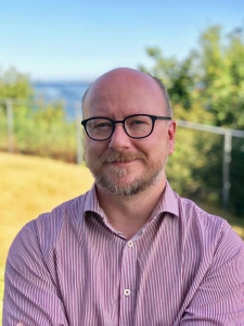 Mann med briller smiler mot kamera