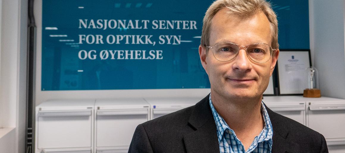 Mann med briller ser mot kamera og smiler.