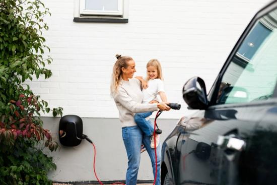 Foto av kvinne som lader elbil i sameie