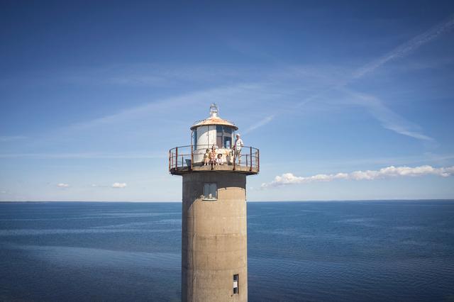 Foto av en fyr framför en blå himmel och ett lugnt hav.