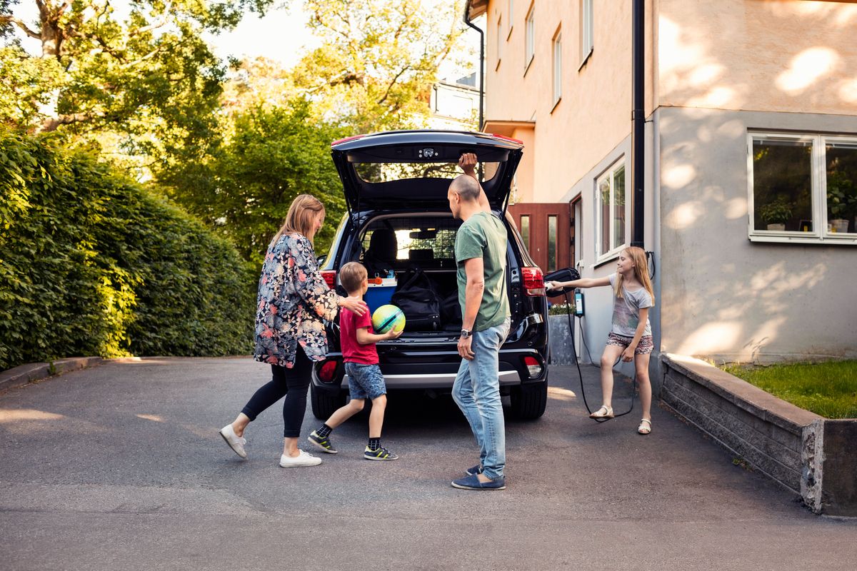 Bilde av familj som laddar utanför en bostadsrättsförening.