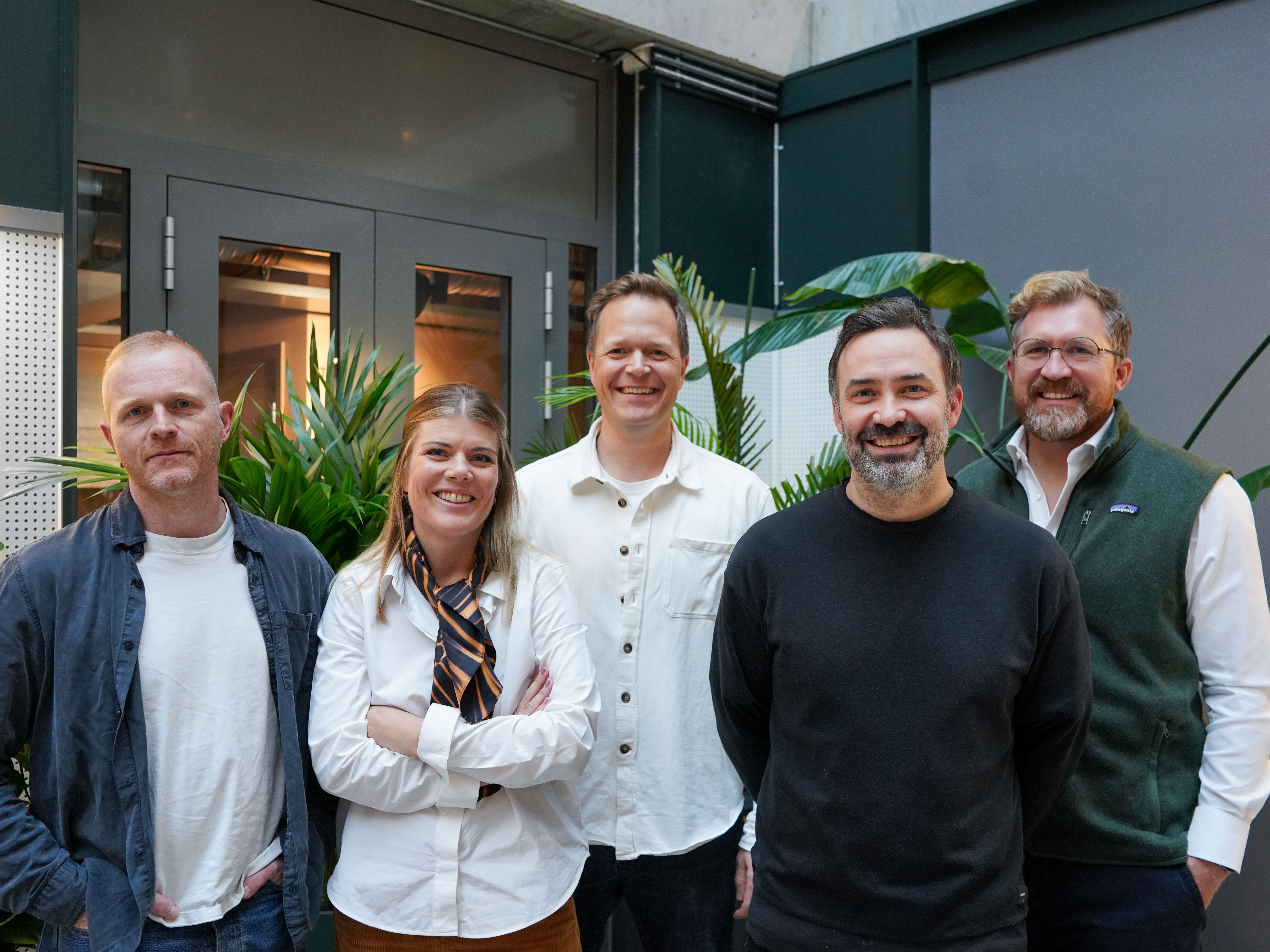 Fire menn og en kvinne står inne i et kontorbygg.