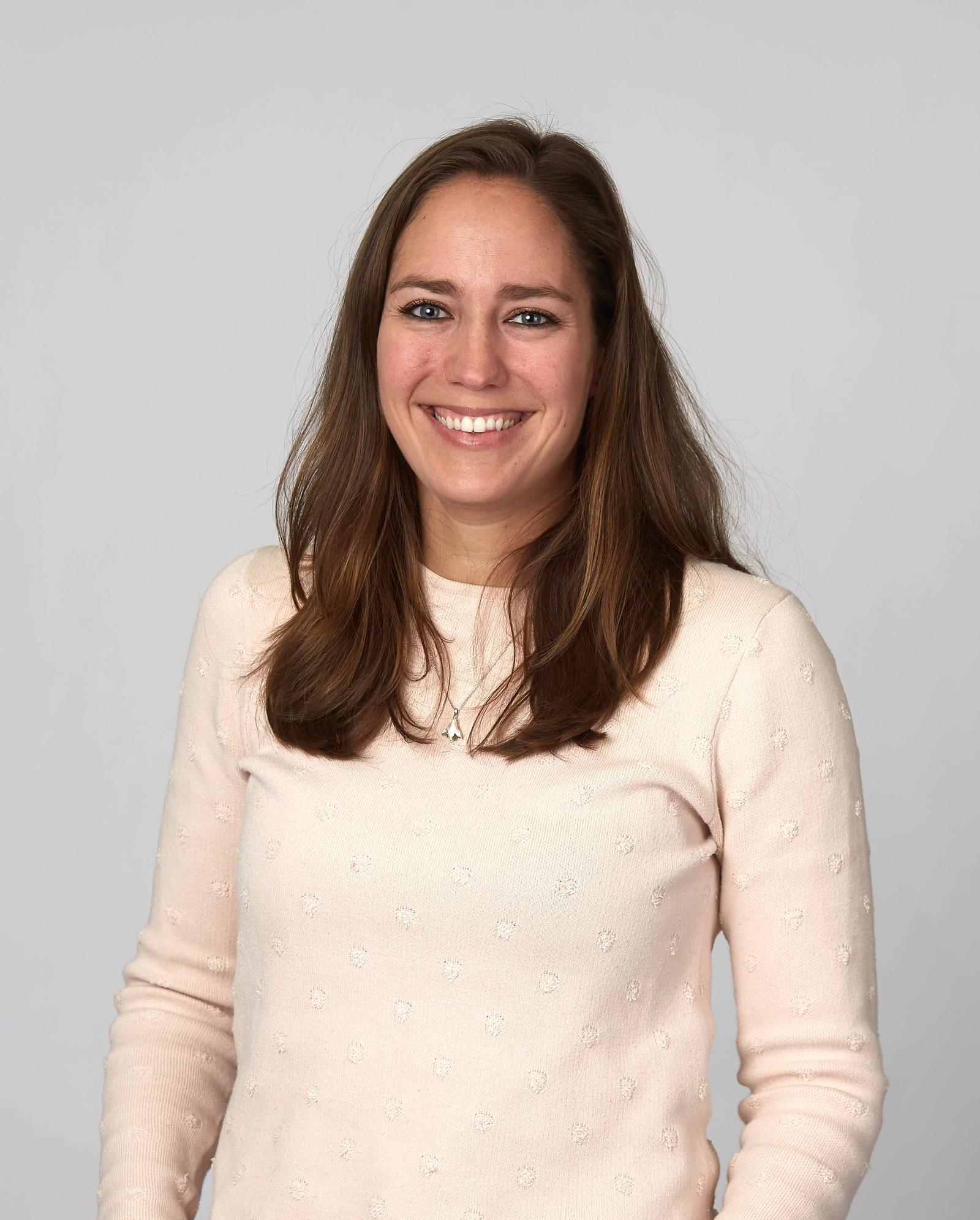 Studiofotografi av dame med langt brunt hår og lyserosa genser.