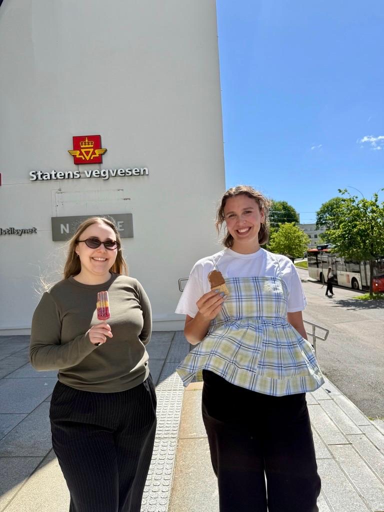 To kvinner står ute med hver sin is, foran bygg med Statens vegvesen-skilt