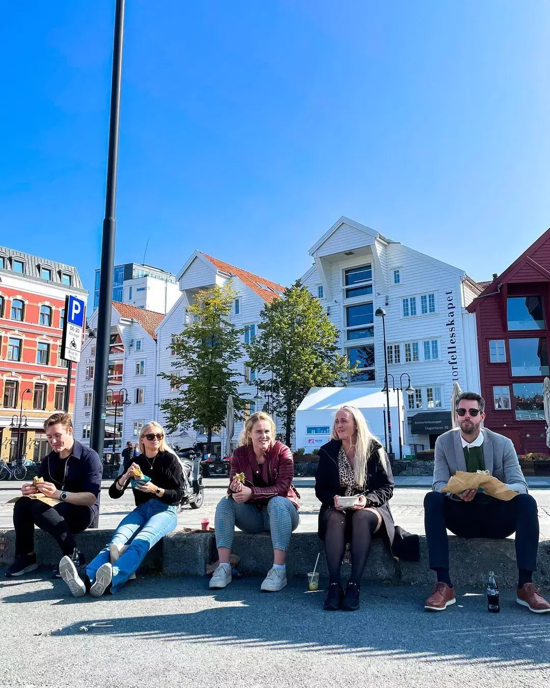 Okse-folk spiser lunsj på fortauskanten i Vågen