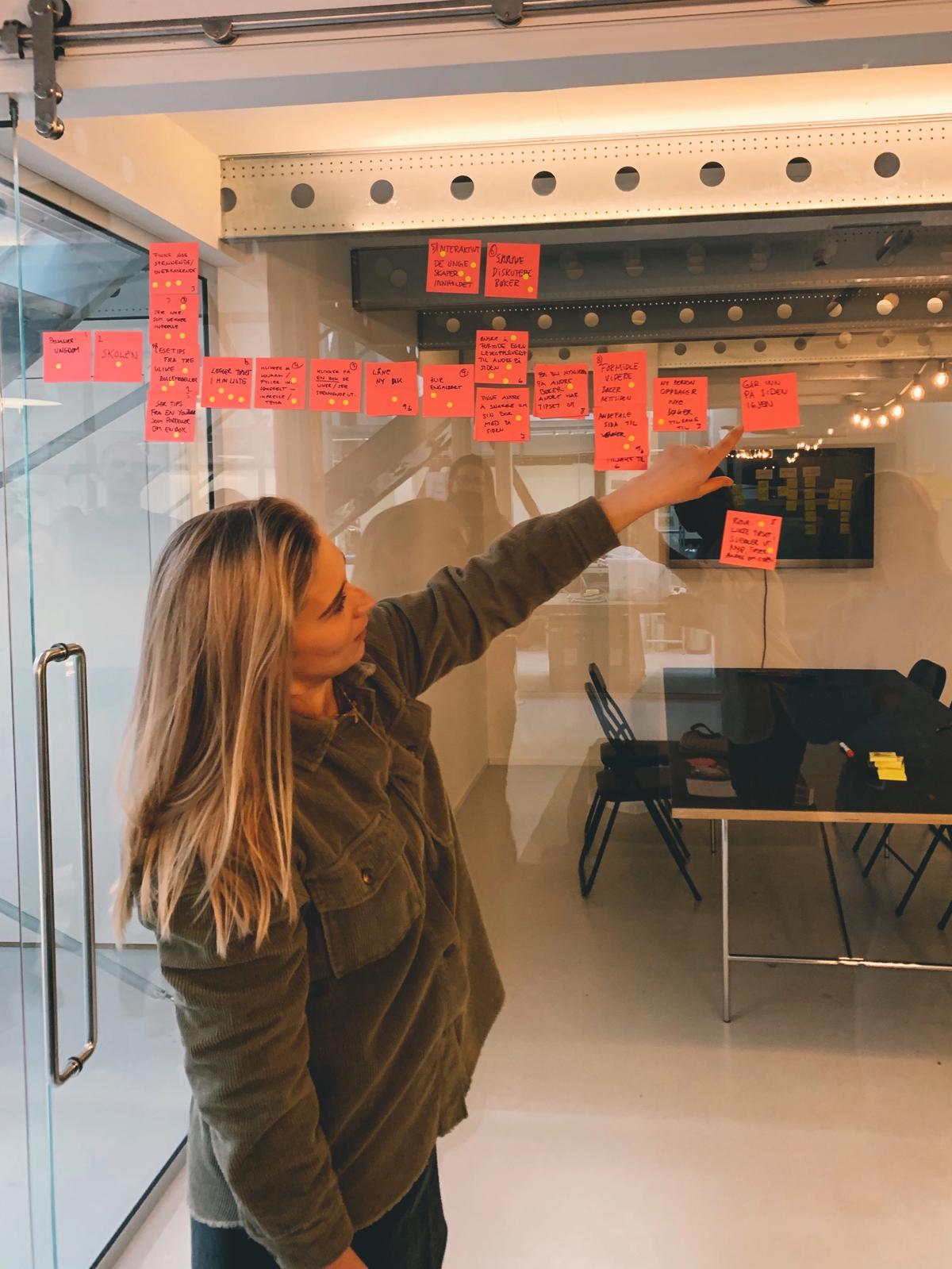 Elisabeth står foran en glassvegg med masse Post-it-lapper