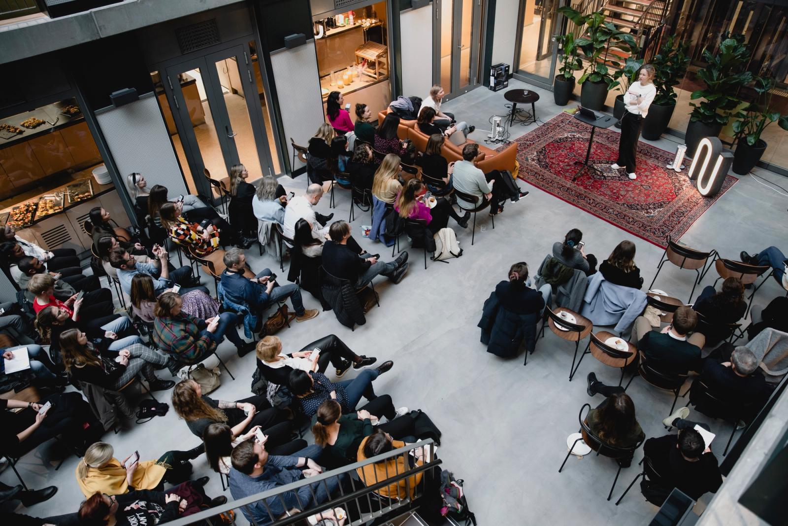 En forsamling mennesker ser på en person som holder foredrag.