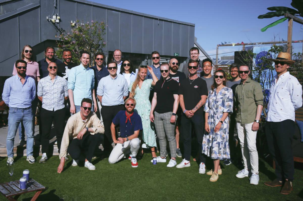 Skalar teamet står samlet ute i solen, for å ta gruppe bilde fra sommerfest