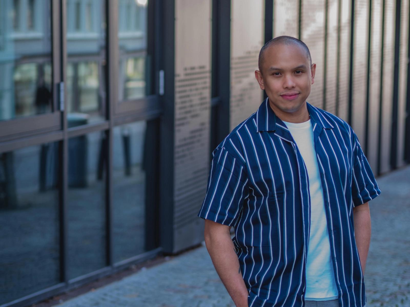 Mann med blå stripete skjorte og hvit t-skjorte.