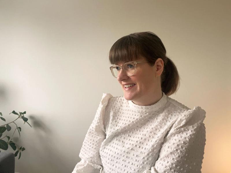 En dame med brunt hår og briller ser mot venstre