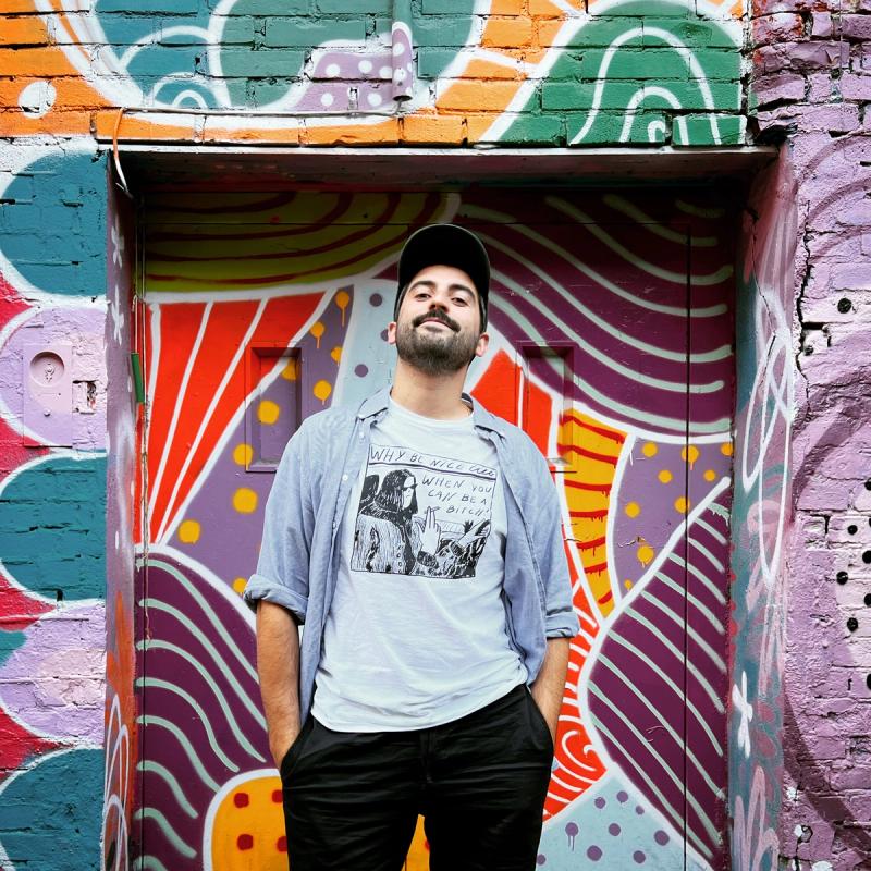 Mann med caps foran graffiti-vegg