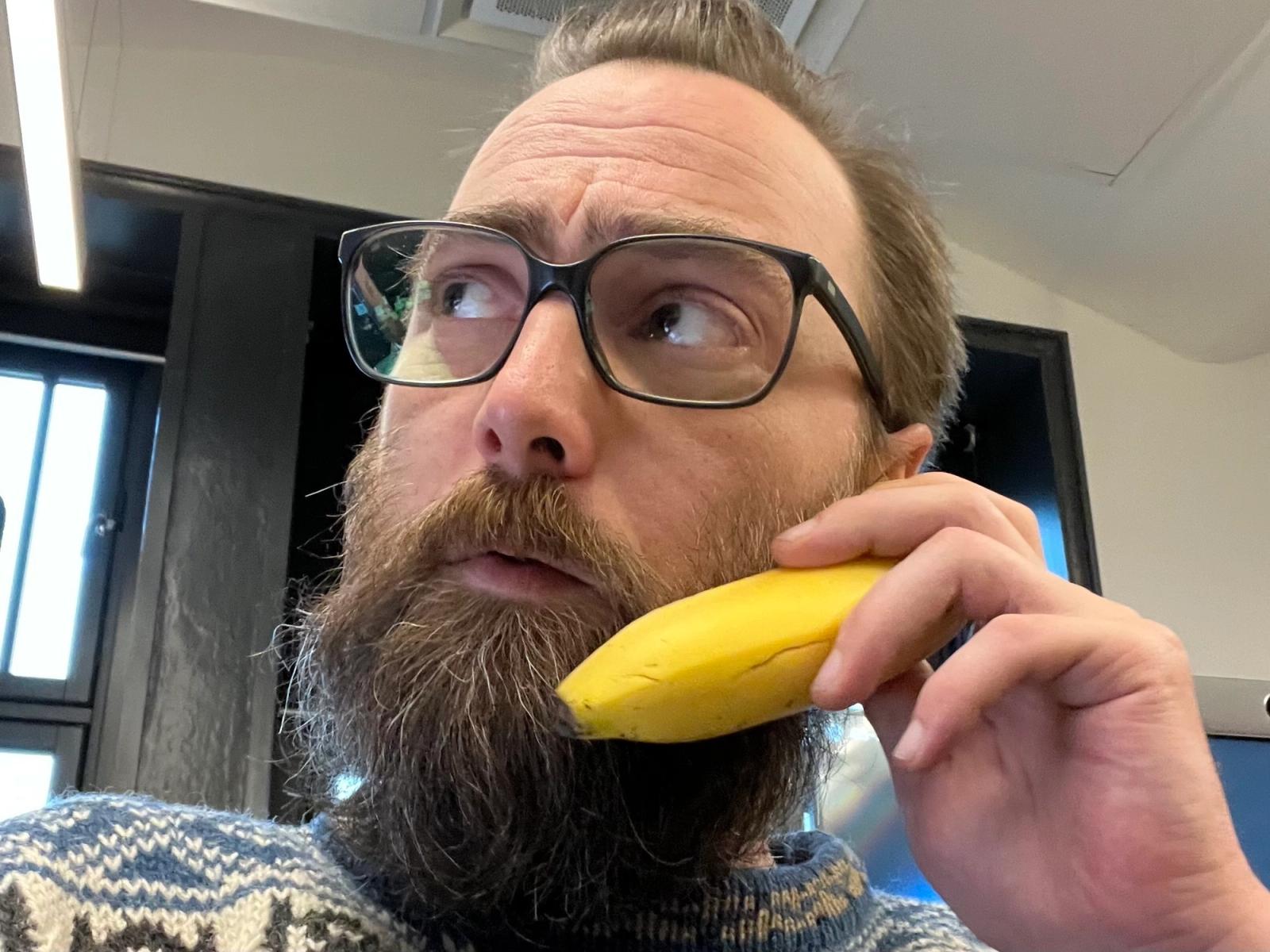 Sideprofil av mann med skjegg, briller og beige caps.