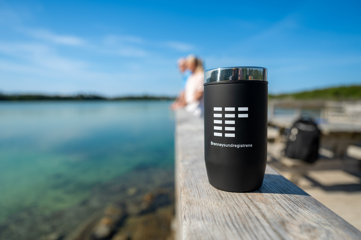 En termoskopp står på en bryggekant