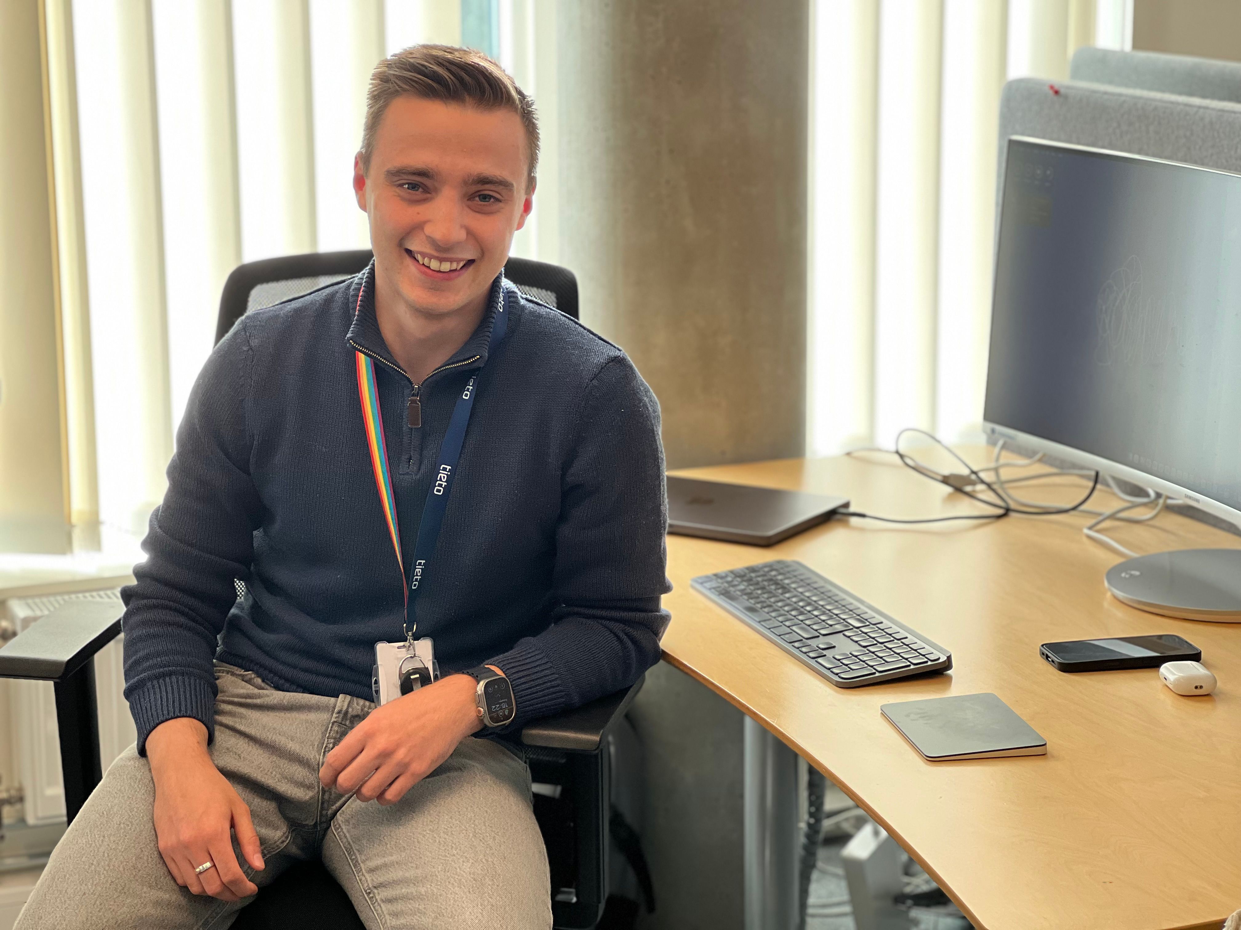 Mann sitter i kontorstol ved siden av et skrivebord