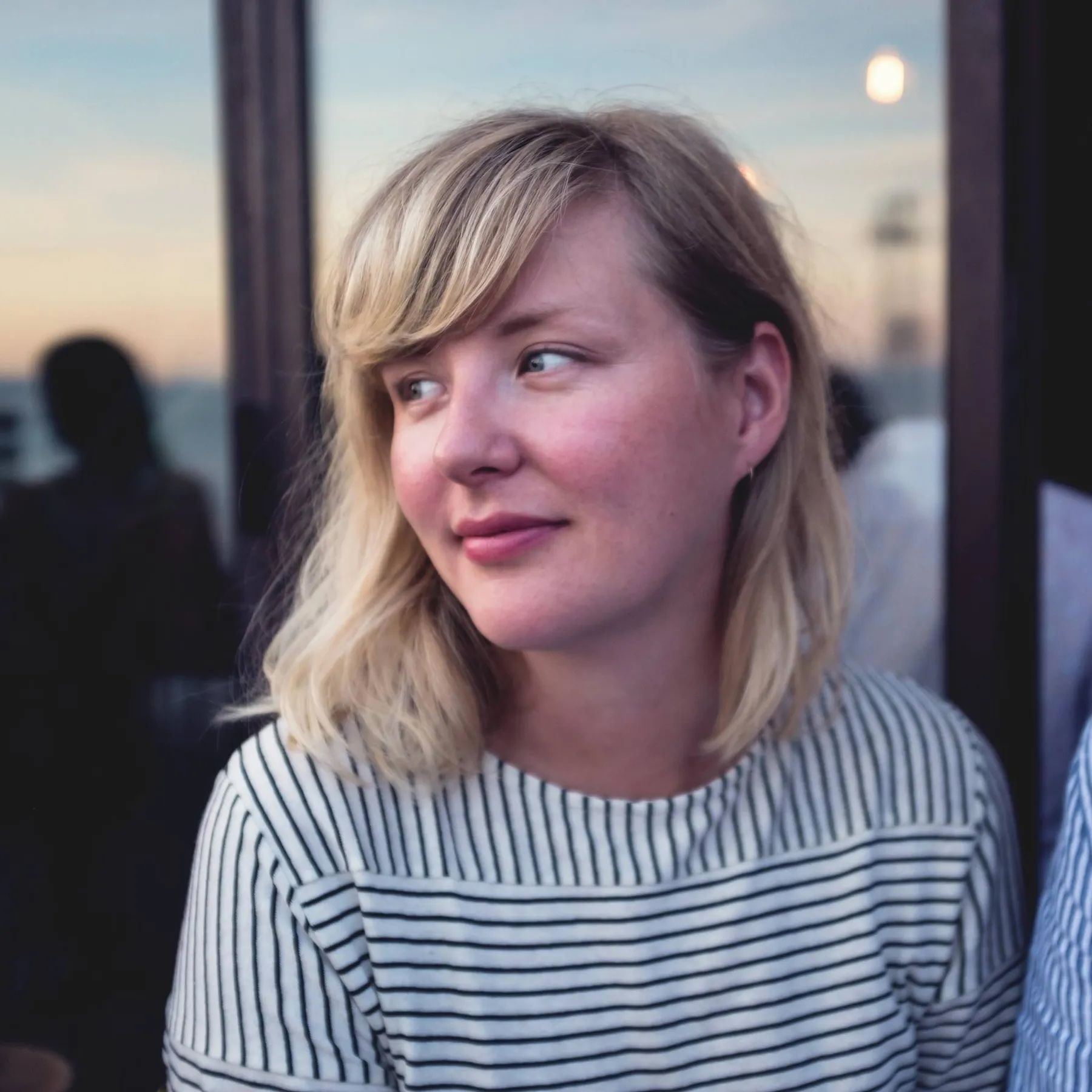 Kvinne med skulderlangt blondt hår i stripete topp.