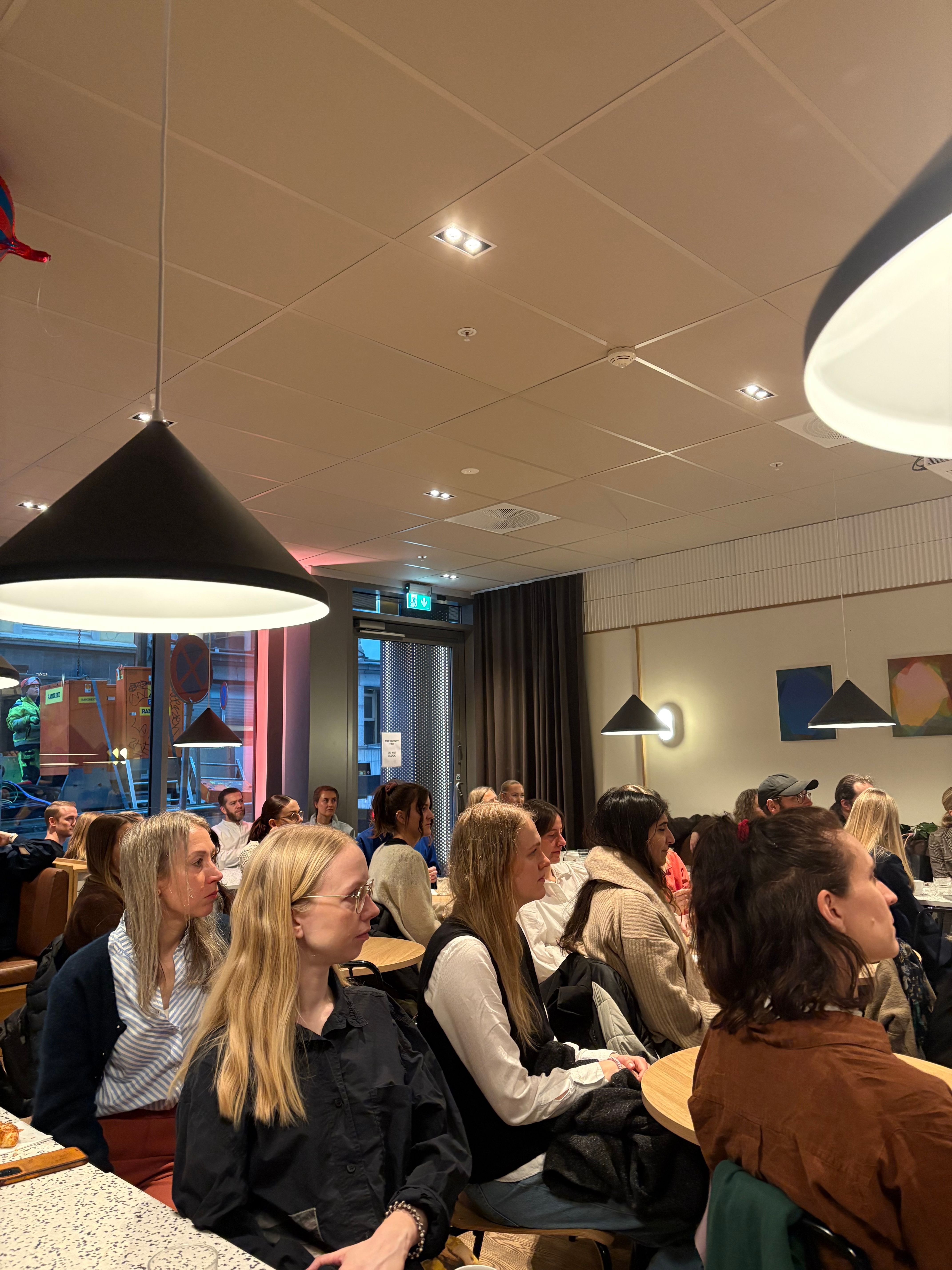 Mennesker sitter rundt bord i et lokale